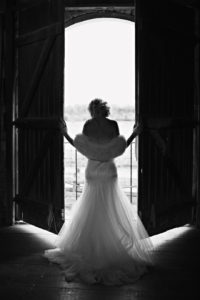 Bride silhouetted in open doorway, black-and-white.