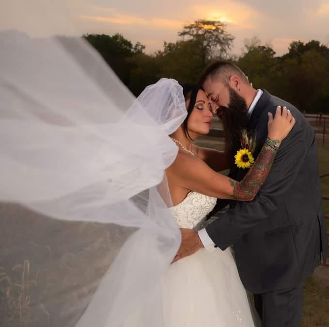 Bride and groom embrace at sunset outdoors.