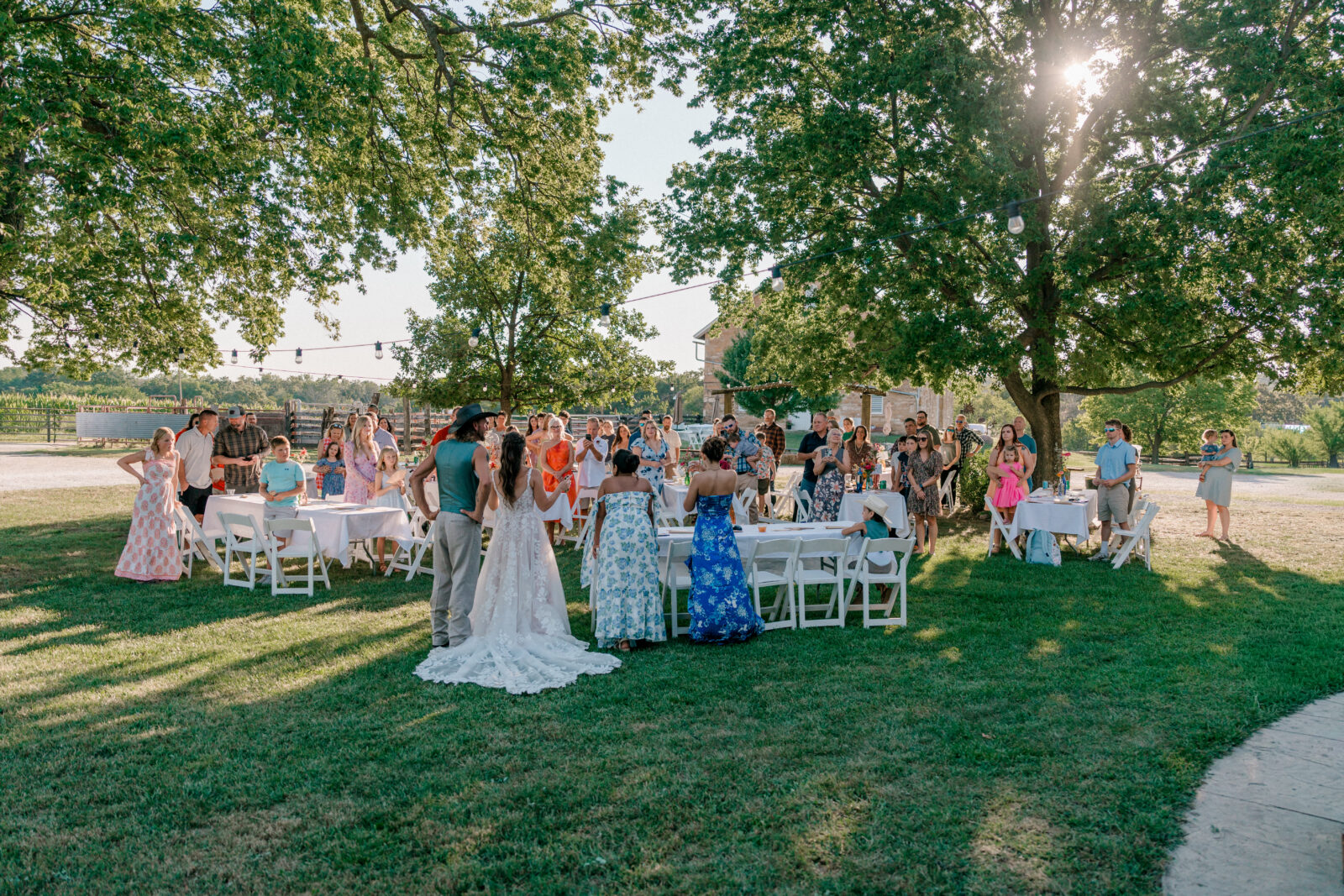 Guests mingle outdoors at a sunny garden wedding reception.